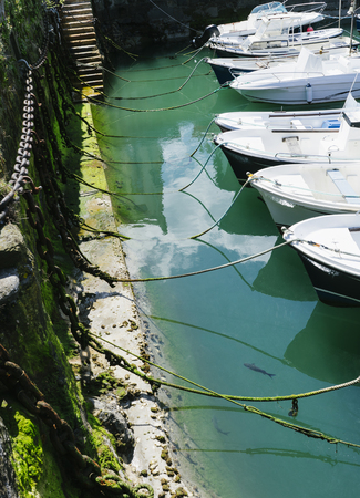 Some boat bright colors on background blue water lake of pier, fishing and boating on summer landscape, holiday travel and sun tourism coast, peaceful ship on backdrop old house and oceanの写真素材