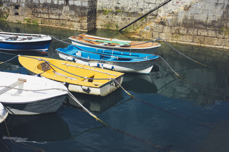 Some boat bright colors on background blue water lake of pier, fishing and boating on summer landscape, holiday travel and sun tourism coast, peaceful ship on backdrop old house and oceanの写真素材