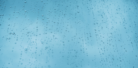 Blue glass with raindrops background texture horizontal top view isolated, rain on the window backdrop, light blue sky, clear water on space blank back, mockup nuture wallの写真素材