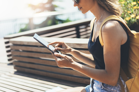 Hipster person holding in hands digital tablet with blank screen, girl photograph on computer on background nature summer park landscape, mock up technology, blur, female hands tourist using gadgetの写真素材