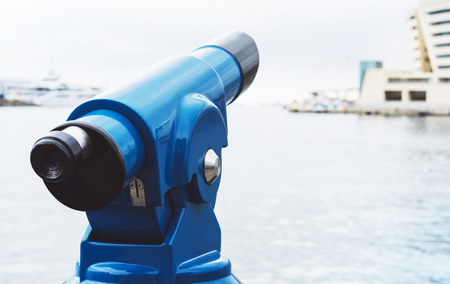 Touristic telescope look at city and sea with sunset view of Barcelona Spain, close up old blue binoculars on background viewpoint the pier port yacht, coin operated in panorama observation sunrise nature, mock upの写真素材