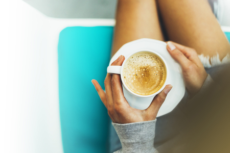 Young woman holding in female hands and drink hot aroma coffee in breakfast time, hipster traveler girl in the morning sun day, holiday relax white cafe, top view blur, vacation atmosphere concept, closeupの写真素材