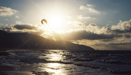 Sunlight sunset on horizon ocean on background seascape atmosphere rays sunrise. Relax view waves sea with kitesurfing on sand beach,  sun light flare nature evening concept, copy space for textの写真素材
