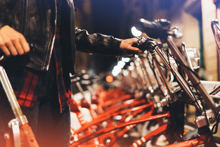 Young girl in black leather jacket using bike on background illumination glow bokeh light in night atmospheric city, hipster biking and riding to work by bicycle on urban street, ecology concept
の写真素材