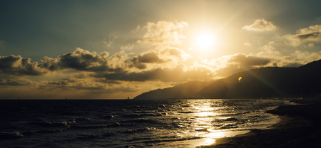 Sunlight sunset on horizon ocean on background seascape atmosphere rays sunrise. Relax view waves sea with kitesurfing on sand beach,  sun light flare nature evening concept, copy space for text
の写真素材