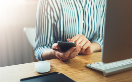 Girl using finger smartphone, woman touch on screen mobile phone in business office atmosphere or home, freelance female hands working on gadget, businesswoman process concept in workspace, crop viewの写真素材
