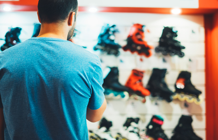 Assortment roller skates isolated in store shop, person choosing and buy color roller-skates on background sun flare, healthy and activity lifestyle concept close up, man consider sport footwearの写真素材
