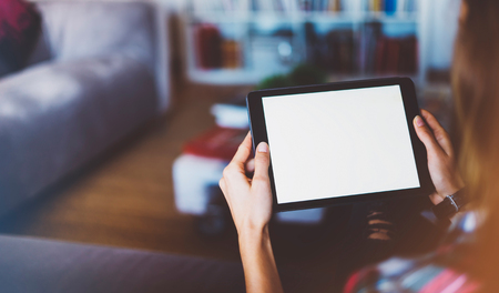 Hipster girl using tablet technology in home atmosphere, girl person holding computer with blank screen on background bokeh, female hands texting on relax holiday, mockup templates gadget, blur lifestyle conceptの写真素材