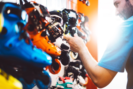 Assortment roller skates isolated in store shop, person choosing and buy color roller-skates on backgraund sun flare, healthy and activity lifestyle concept close up, man consider sport footwear for roller skateの写真素材