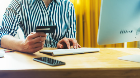 Hipster holding in hands credit card, women shopping online purchase, enjoy to buy internet, working at office with monitor computer, freelance manager typing on keyboard, work process concept in workspace の写真素材