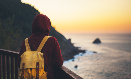 Hipster hiker tourist with backpack looking of amazing seascape sunset on background blue sea, girl enjoying ocean horizon, panoramic sunrise, traveler relax holiday concept, sunlight view in trip vacationの写真素材