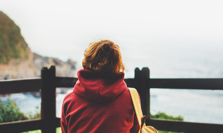 Hipster hiker tourist with backpack looking on seascape sunset, background blue sea and mountain, girl enjoying ocean horizon, panoramic sunrise, traveler relax holiday concept, sunlight view in trip vacationの写真素材