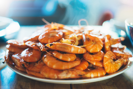Isolated prepared orange shrimp on background table on kitchen, closeup of fresh prawn products in restaurant, shellfish sea food on plate, group cooked boiled seafood, ocean dieting shrimps on cuisineの写真素材