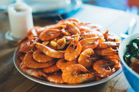 Isolated prepared orange shrimp on background table on kitchen, closeup of fresh prawn products in restaurant, shellfish sea food on plate, group cooked boiled seafood, ocean dieting shrimps on cuisineの写真素材