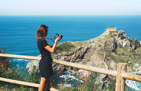 Tourist traveler photographer making pictures sea scape on photo camera on background ocean...