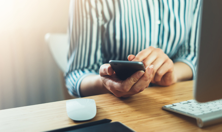 Girl using finger smartphone, woman touch on screen mobile phone in business office atmosphere or home, freelance female hands working on gadget, businesswoman process concept in workspace, crop viewの写真素材