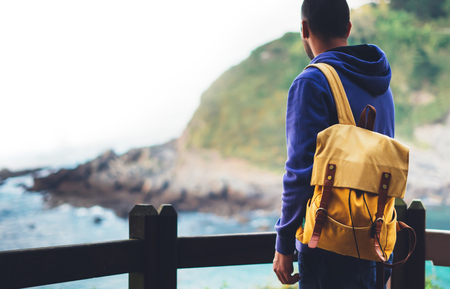 traveler relax holiday concept, guy enjoying ocean horizon, panoramic sunrise, sunlight view in trip vacation, hipster hiker tourist with backpack looking on seascape sunset, background blue sea and mountainの写真素材