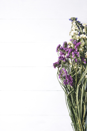 Bouquet of dried wild flowers on white table background  with natural wood vintage planks wooden texture top view vertical, empty space for publicity information or advertising textの写真素材