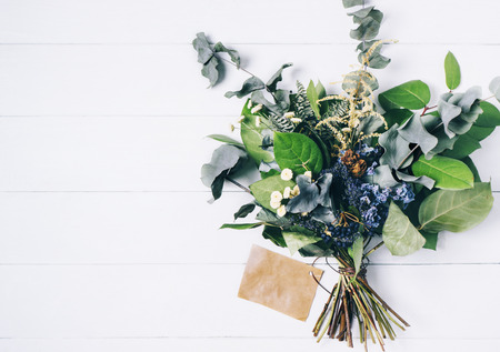 Bouquet of dried wild flowers on white table background  with natural wood vintage planks wooden texture top view horizontal, empty space for publicity information or advertising textの写真素材