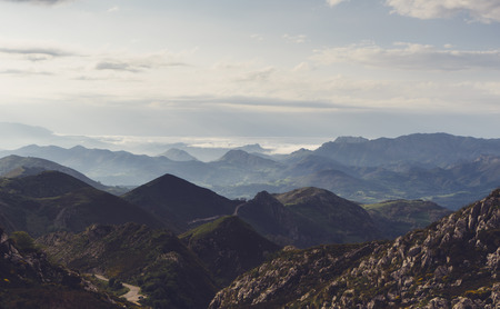 Green valley on background dramatic sky and clouds. Panorama horizon view of scenery foggy hills Northern Spain alps.の写真素材