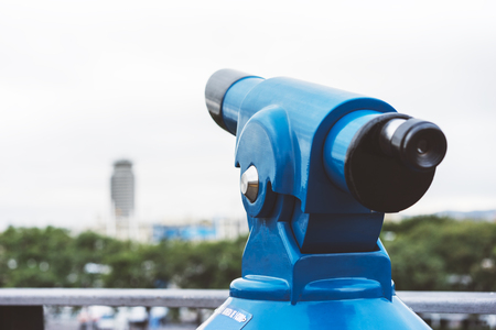 Touristic telescope look at the city with view of Barcelona Spain, close up old blue binoculars on green nature background viewpoint, coin operated in panorama observation, mockupの写真素材