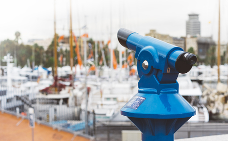 Touristic telescope look at the city with view of Barcelona Spain, close up old blue binoculars on background viewpoint  the pier port yacht, coin operated  in panorama observation nature, mockupの写真素材