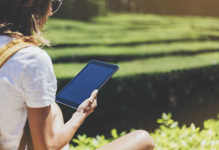 Hipster girl with backpack, sunglasses and vintage photo camera using tablet computerの写真素材