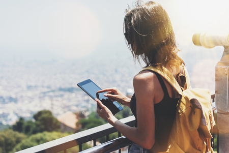 Hipster girl with backpack holding gadget in observation view.の写真素材