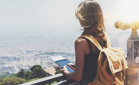 Hipster girl with backpack holding gadget in observation view.の写真素材