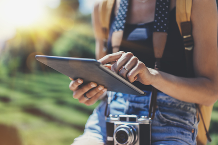 Hipster girl with backpack and vintage photo camera using tablet computer close upの写真素材