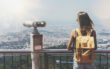 Hipster young girl with bright backpack looking on observation deck and travel plan.の写真素材
