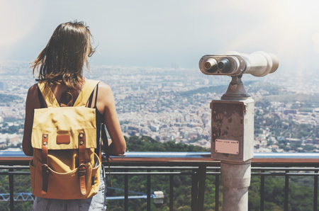 Hipster young girl with bright backpack looking on observation deck and travel plan.の写真素材