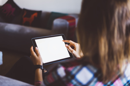 Hipster girl using tablet technology in home, blogger girl person holding computer with blank screen...