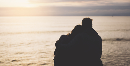 Couple hugging on background beach ocean sunrise, meeting of lovers concept, silhouette two romantic people cuddling and looking on view evening seascape, hipster enjoy sunset together, travel holidays vacation relaxの写真素材