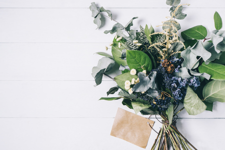 Bouquet of dried wild flowers on white table background  with natural wood vintage planks wooden texture top view horizontal, empty space for publicity information or advertising textの写真素材
