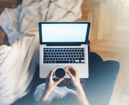 Girl in a chair in a homely atmosphere with an open laptop with a empty blank screen monitorの写真素材