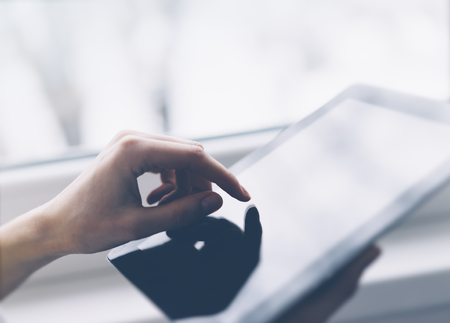 Closeup of a person pointing finger to a computer monitor with a blank screen blue against a...