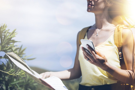 Hipster young girl with bright backpack looking at phone and map. Said view tourist traveler on...
