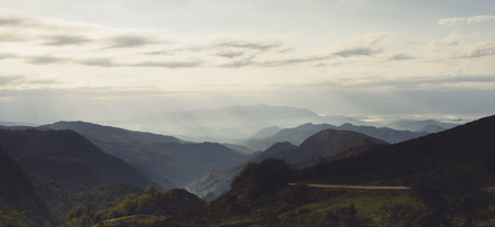 Green valley on background dramatic sky and clouds. Panorama  horizon view of scenery  foggy hills Northern Spain alps. Travel mockup concept in morning time. Sunset in the mountain natural landscape park.の写真素材