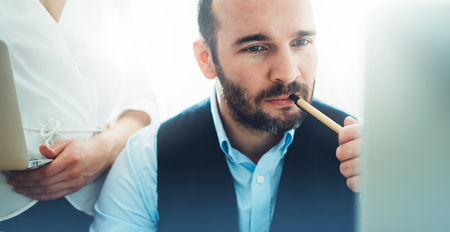 Bearded young businessman working on modern office. Consultant man thinking looking in monitor computer. Manager coworking on workplace, discussio startup project concept in studio with colleagueの写真素材