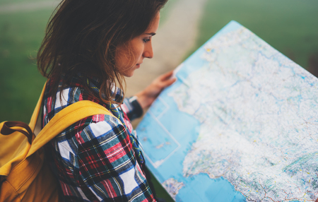Hipster young girl with backpack holding in hands and looking on map spain of foggy mountain, tourist traveler hiker on background valley landscape panoramic view, trip in northern spain basque countryの写真素材
