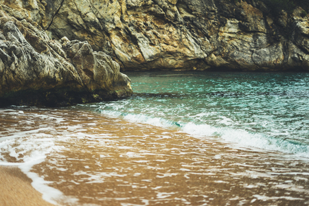 coastline beach on sunny day background rocky coast, gold sand close up blur, tourism relax calm concept mockup, seascape perspective vacation, summer seashore on blue sea waves and sand at sunsetの写真素材