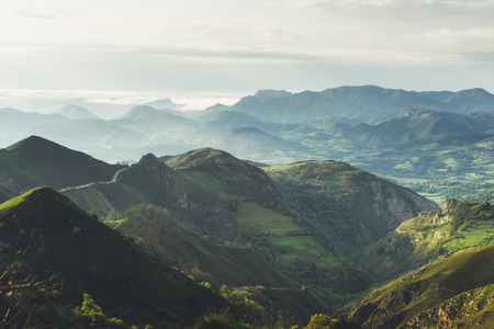 morning mist in the mountain peaks on natural landscape. Green valley on background foggy dramatic sky. Panorama horizon perspective view of scenery hills Northern Spain mountain tops. Travel mockup conceptの写真素材