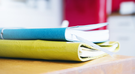 close-up of brightly colored notebooks on wooden table on red background side view of the object,...
