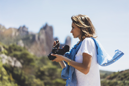 Tourist traveler photographer taking pictures of amazing landscape on vintage photo camera on background valley view mockup sun flare, hipster girl enjoying peak of foggy mountain, nature holiday conceptの写真素材