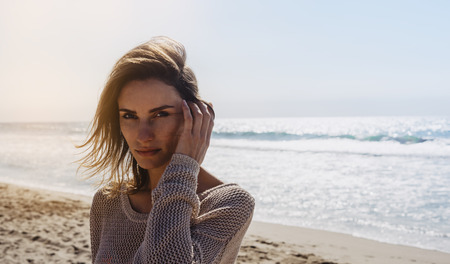 portrait young pretty girl looking on summer beach, hipster in sand coastline on background seascape horizon blue sun ocean, beauty model posing in crochet jacket in nature outdoors, relax lifestyle conceptの写真素材