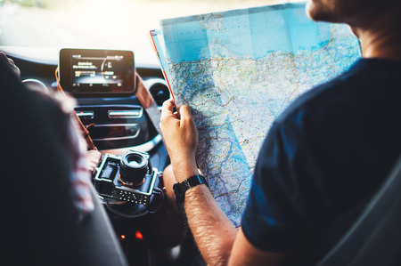 tourist traveler driving and hold in male hands europe cartography, view and plan tourist way road, trip in transportation auto, hipster man looking and point finger on location navigation map in carの写真素材