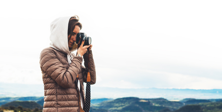 photographer traveler on green top on mountain, tourist looking holding in hands digital photo camera, hiker taking click photography, girl enjoy nature panoramic landscape in trip, relax holiday hobby conceptの写真素材