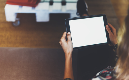 Hipster girl using tablet technology in home atmosphere, girl person holding computer with blank screen on background bokeh, female hands texting on relax holiday, mockup templates gadget, blur lifestyle conceptの写真素材