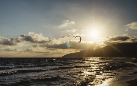 Sunlight sunset on horizon ocean on background seascape atmosphere rays sunrise. Relax view waves sea with kitesurfing on sand beach,  sun light flare nature evening concept, copy space for textの写真素材